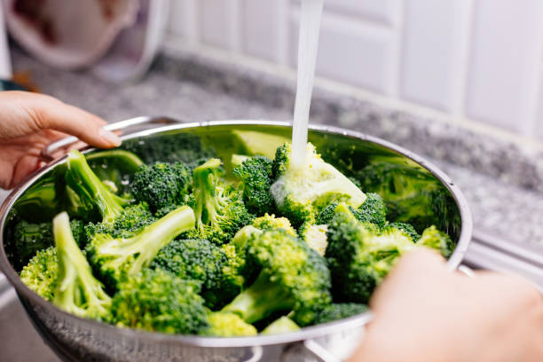 istock Woman washing broccoli in the kitchen sink 1184373848