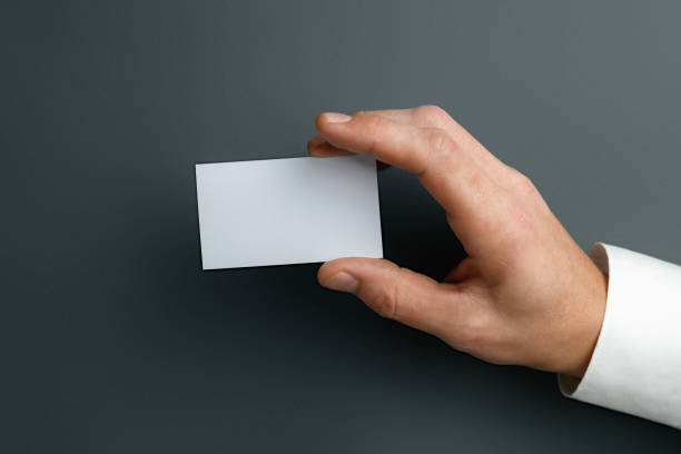 istock Male hand holding a blank business card on grey background for text or design 1184374748