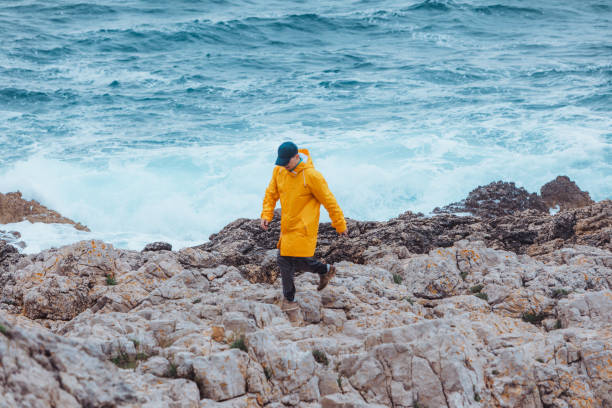 istock man walking by rock to storming sea. copy space 1184375184