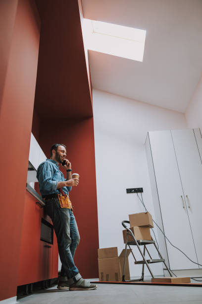 istock Smiling handyman drinking coffee during home repair 1184375553