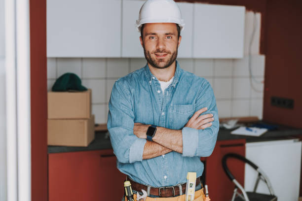 istock Smiling handyman with tool belt posing in the kitchen 1184378591