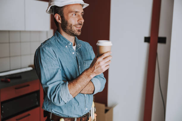 istock Smiling repairman is resting with coffee in flat 1184378627