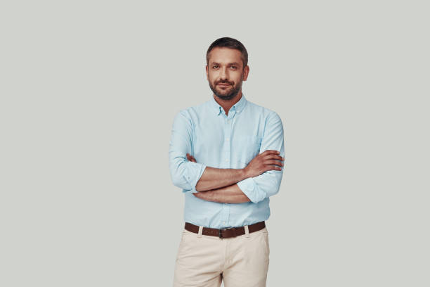 istock Handsome young man looking at camera and smiling while standing against grey background 1184378972