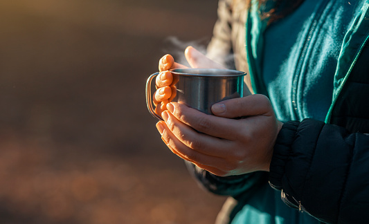 Cozy moments. Woman holding camping cup with hot drink, cropped, copy space