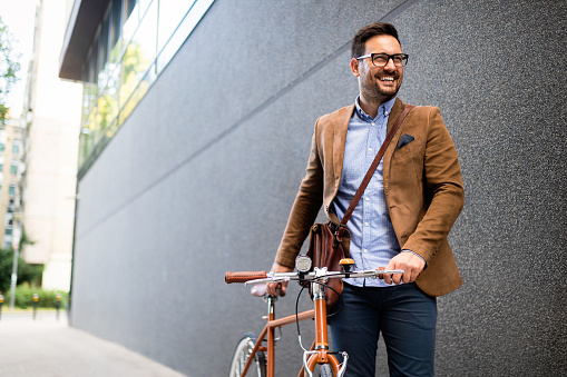 Feliz joven y elegante hombre de negocios va a trabajar en bicicleta photo