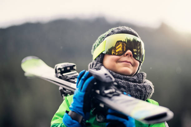 porträt eines kleinen skifahrers, der seine skier trägt - ski resort hut snow winter stock-fotos und bilder