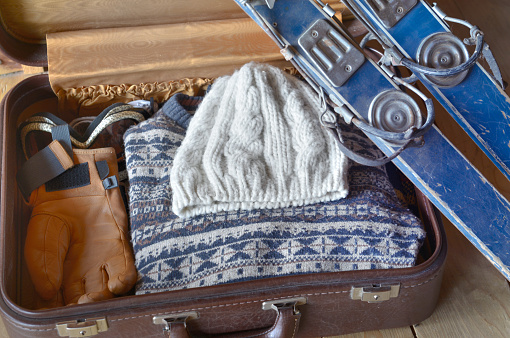 old ski against  a suitcase opening  with warm clothing