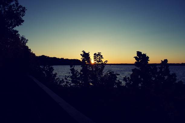 istock Sun setting over Belmont Bay with silhouette of trees and cliff 1184387610