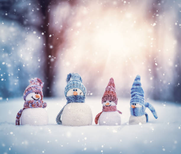 little knitted snowmans on soft snow on blue background