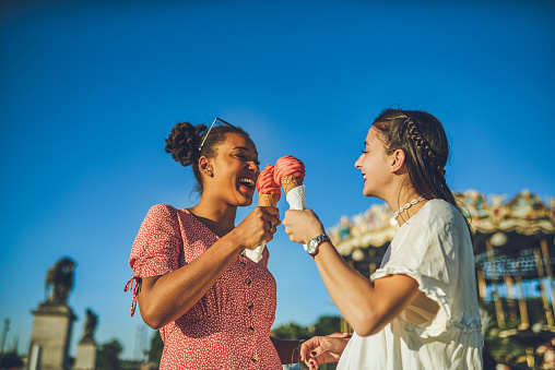 Shot of two happy young women eating ice cream together at a carnival
