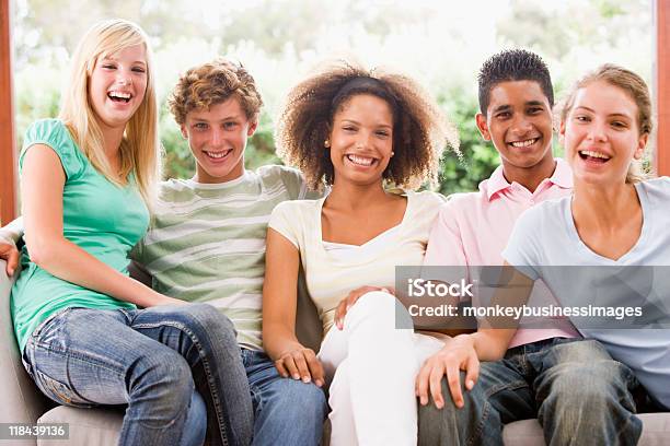 Grupo De Adolescentes En Un Sofá En La Sala De Estar Foto de stock y más banco de imágenes de 14-15 años