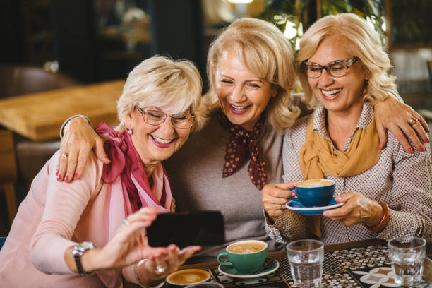 istock Three senior ladies taking selfie with smart phone in cafe 1184393227