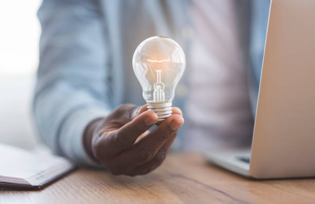 istock Black businessman holding illuminated light bulb in hand 1184393705