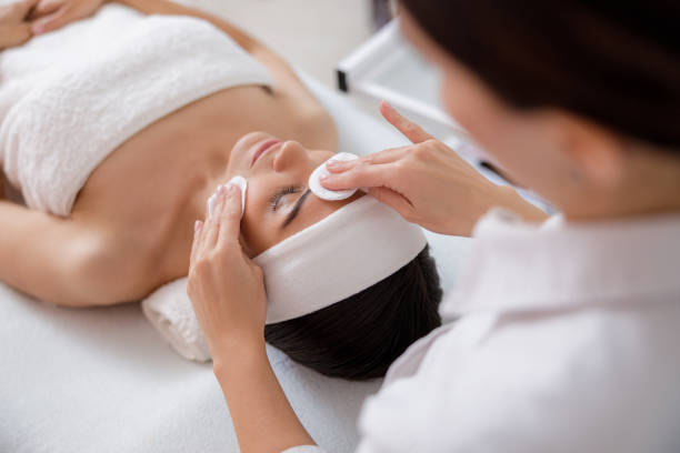 istock Beautician hands cleaning lady face with cotton pads 1184393774
