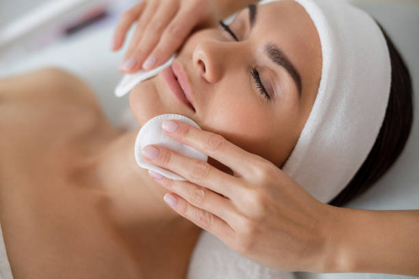 istock Beautician hands wiping lady face with cotton pads 1184393814