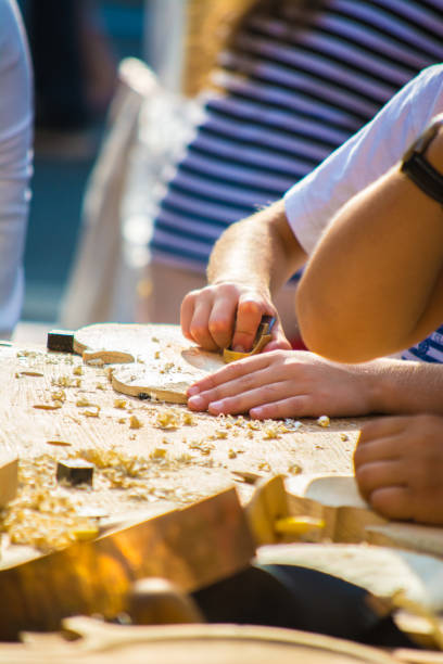 les enfants apprennent à faire du violon personnalisé et d'autres instruments de musique dans les classes de fablab en plein air. formation de joiner sur makerfaire. - fertigung photos et images de collection