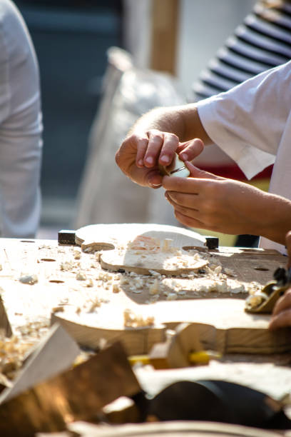 as crianças aprendem a fazer violino personalizado e outros instrumentos musicais em aulas de fablab ao ar livre. marceneiro está treinando em makerfaire. - fertigung - fotografias e filmes do acervo