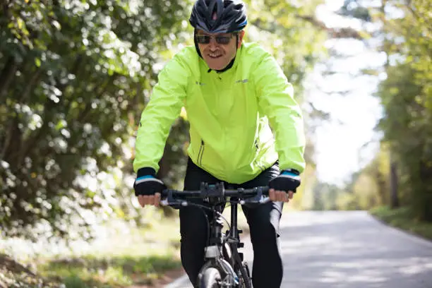 Photo of Smiling Senior Man Cycling on Country Road