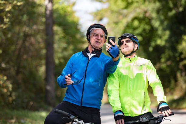 istock Smiling Senior Men Cyclers Taking a Selfie With Mobile Phone on Country Road 1184395385