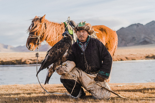 Portrait of eagle hunter with horse near the river  in Mongolia