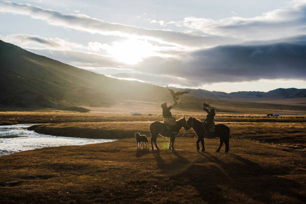 Young female Kazakh eagle hunter together with her horse at riverbank in Bayan Olgii, West Mongolia