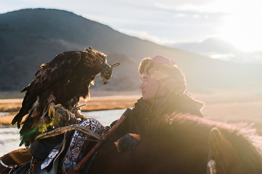 Portrait of eagle hunter with horse near the river  in Mongolia