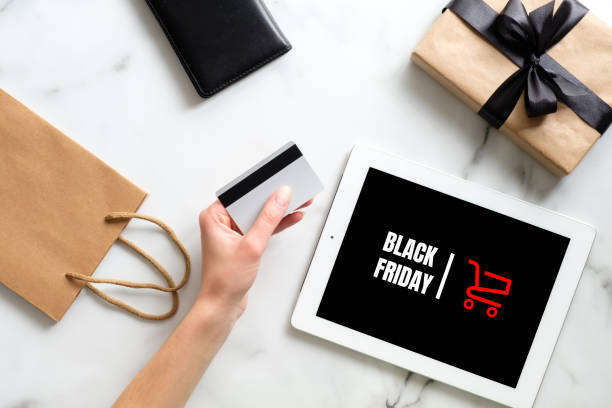 istock Black friday concept. Hand with debit card make purchase over marble table with tablet, gift box, shopping bag 1184399453