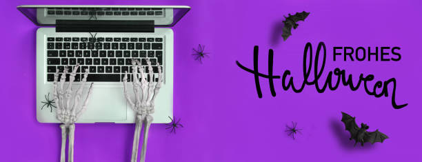 mani scheletro digitando laptop e testo di halloween in tedesco - skeleton key key computer keyboard laptop foto e immagini stock