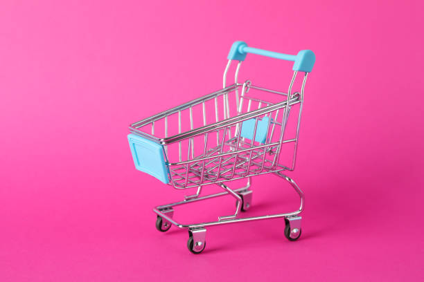 istock Small shopping cart on pink background, space for text 1184401226