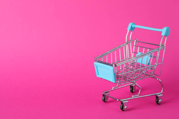 istock Small shopping cart on pink background, space for text 1184401287