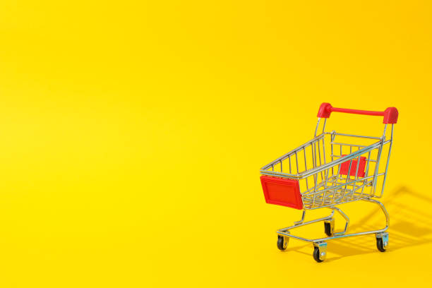 istock Small shopping cart on yellow background, space for text 1184401360
