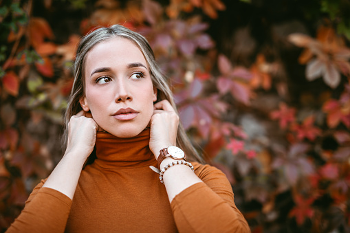 Portrait of pretty young blonde woman in autumn vibrant forest looking away