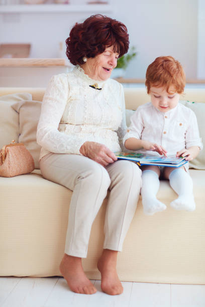 自宅でひ孫と一緒に美しい成熟した女性(80歳)の肖像画、一緒に教育本を読む - female 80 plus years vertical people ストックフォトと画像