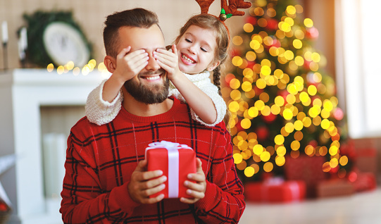 happy family father and child daughter giving christmas gift and embracing