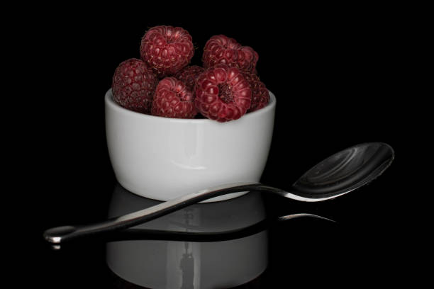 istock Fresh crimson raspberry isolated on black glass 1184411104