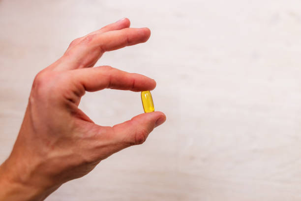 mão do homem que prende o comprimido herbal do suplemento, comendo saudável - zinc mineral nutritional supplement pill - fotografias e filmes do acervo