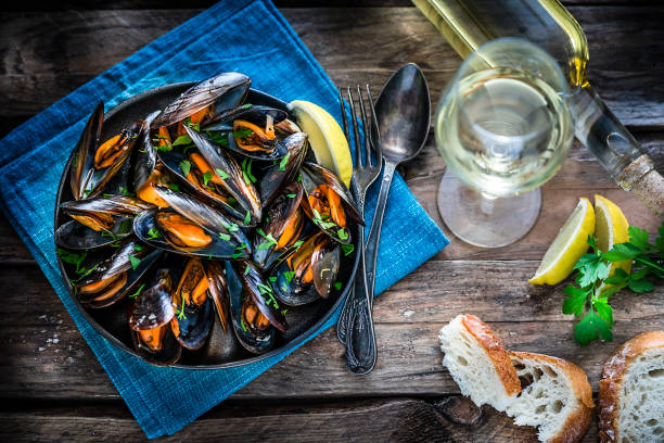 istock Steamed mussels and white wine on rustic wooden table 1184412138