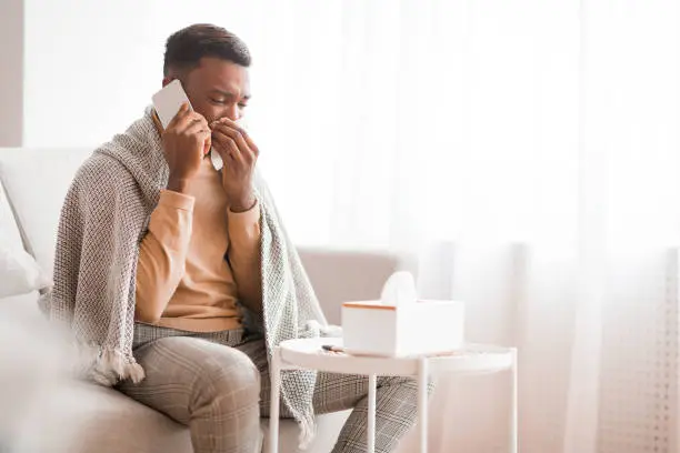 Photo of Man Calling Doctor Blowing Nose In Paper Tissue At Home