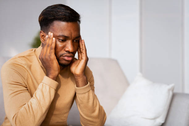 istock Man Having Migraine Massaging Temples Sitting On Sofa At Home 1184412715