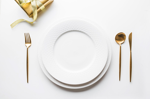 Elegant table setting with golden cutlery on white background. Top view. Top view. Romantic dinner. Christmas holiday time. Xmas party.