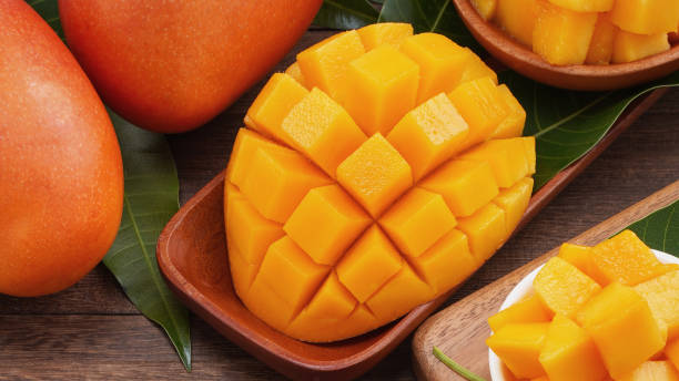 istock Fresh mango,beautiful chopped fruit with green leaves on dark wooden table background. Tropical fruit design concept. Flat lay. Top view. Copy space 1184414014