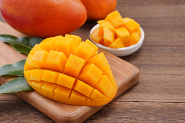 istock Fresh mango,beautiful chopped fruit with green leaves on dark wooden table background. Tropical fruit design concept. Flat lay. Top view. Copy space 1184414017