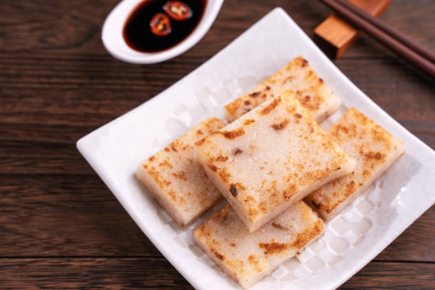 gâteau délicieux de navet, gâteau local traditionnel chinois de radis de plat dans le restaurant avec la sauce de soja et les baguettes, fermez vers le haut, copiez l'espace. - chopsticks rest photos et images de collection