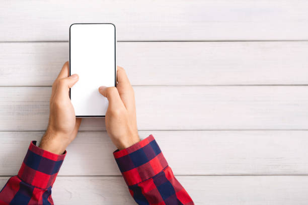 istock Man messaging on smartphone with blank screen over wooden background 1184414486