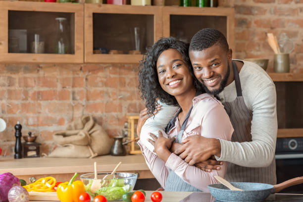 istock Handsome african man hugging his wife while cooking at kitchen 1184414883
