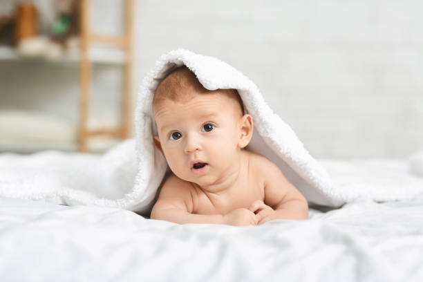istock Cute newborn boy peeking out under soft white blanket 1184414894
