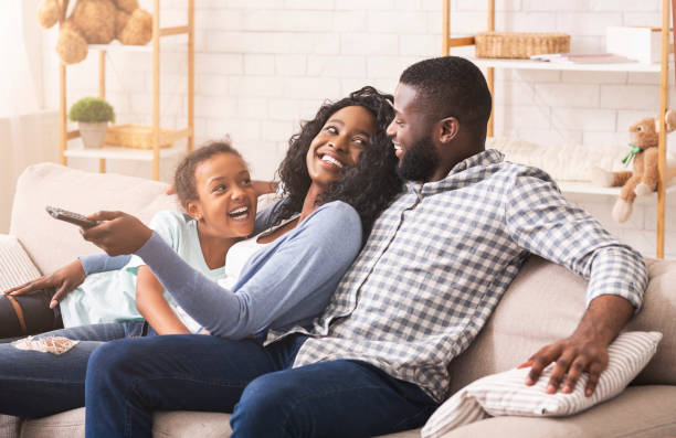 familia alegre divirtiéndose juntos, relajándose en el sofá en casa - three person family fotografías e imágenes de stock