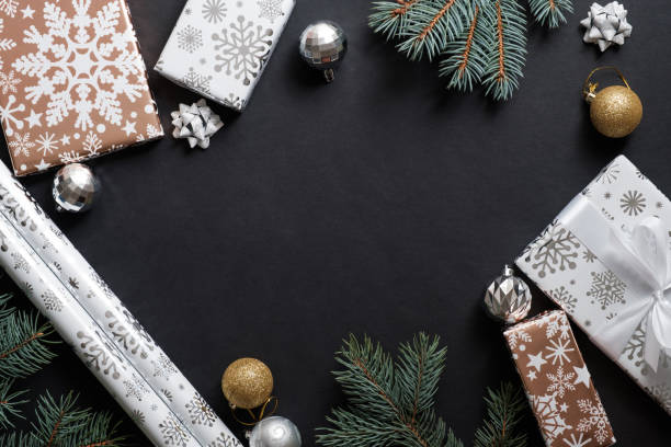 Christmas composition with gift boxes, paper's rools and decorations on black background. Preparation for holidays concept. Flat lay, top view, overhead