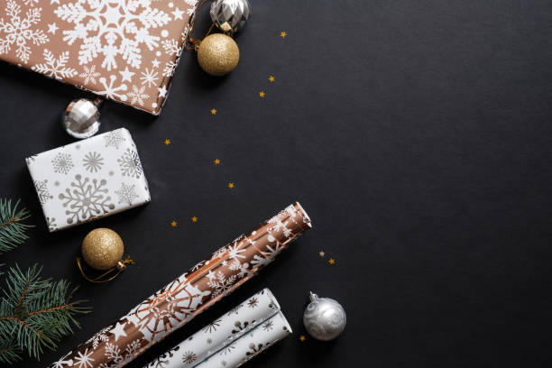istock Christmas composition with gift boxes, paper's rools and decorations on black background. Preparation for holidays concept. Flat lay, top view, copy space 1184418719
