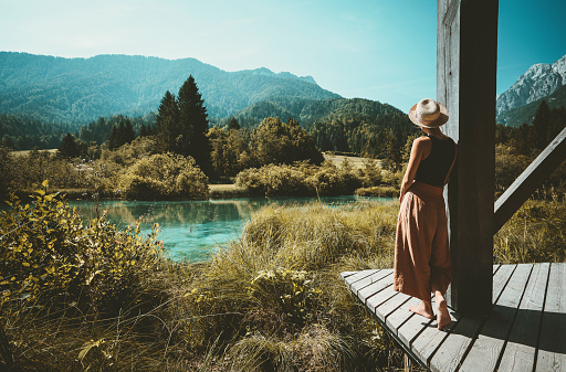 Young woman enjoying freedom on nature outdoors. Travel, Relaxation, Lifestyle Image. Amazing view on Zelenci (into English means - green) natural reserve in Slovenia, Europe. Nature background.